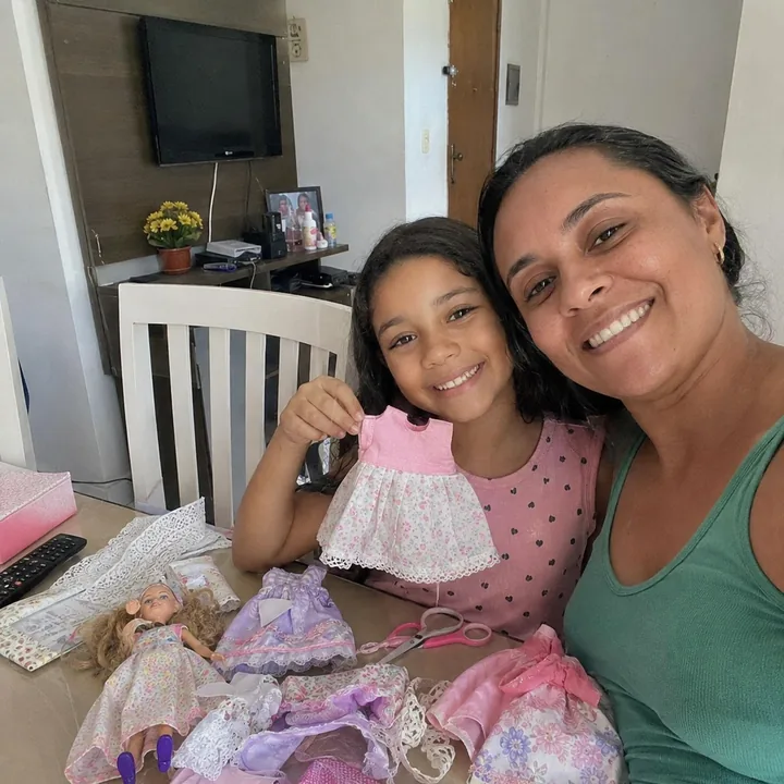 Mom and daughter showing a handmade doll dress